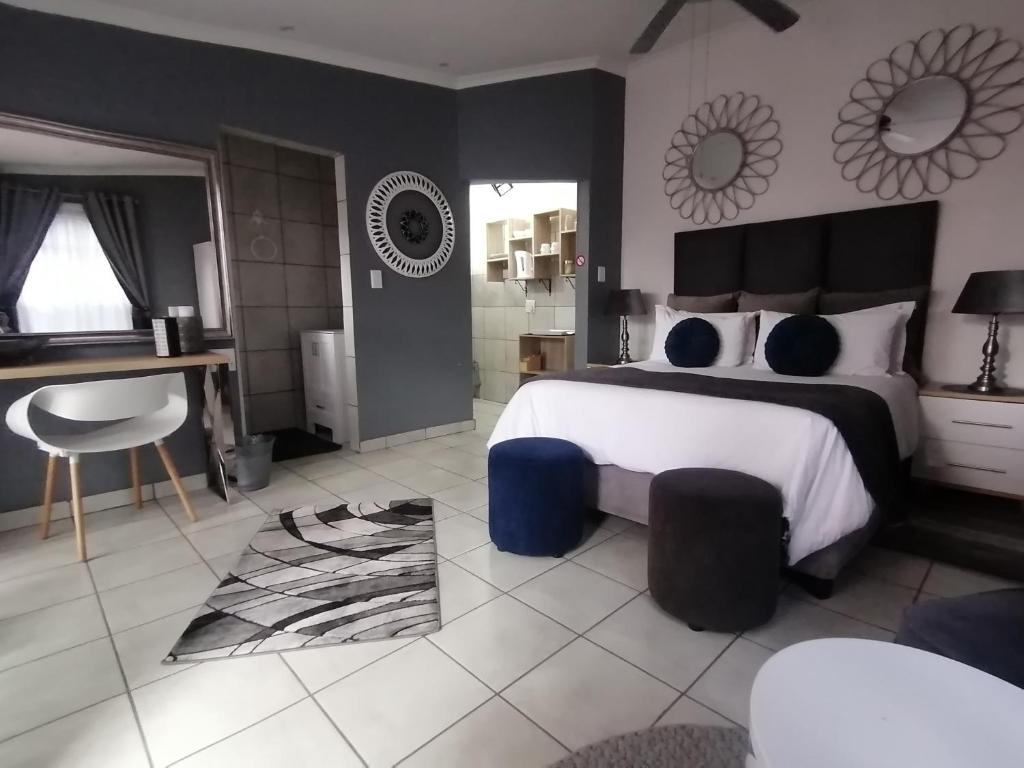 een slaapkamer met een groot bed en een badkamer bij Roxy's Rest Guest House in Vanderbijlpark