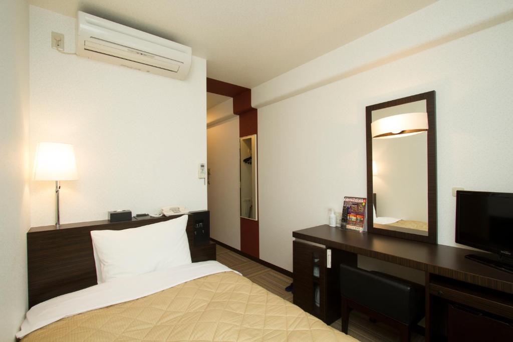 a hotel room with a bed and a mirror at Ariston Inn Kanda Kitakyusyu Airport in Kanda