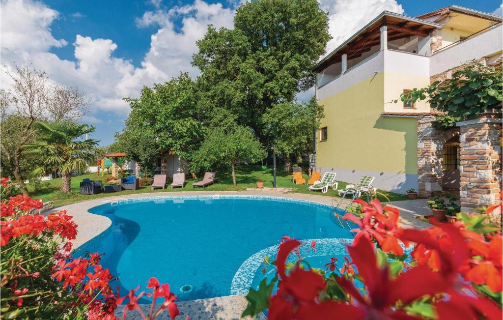 a pool in front of a house with red flowers at 2 Bedroom Nice Apartment In Veli Jezenj in Veli Ježenj