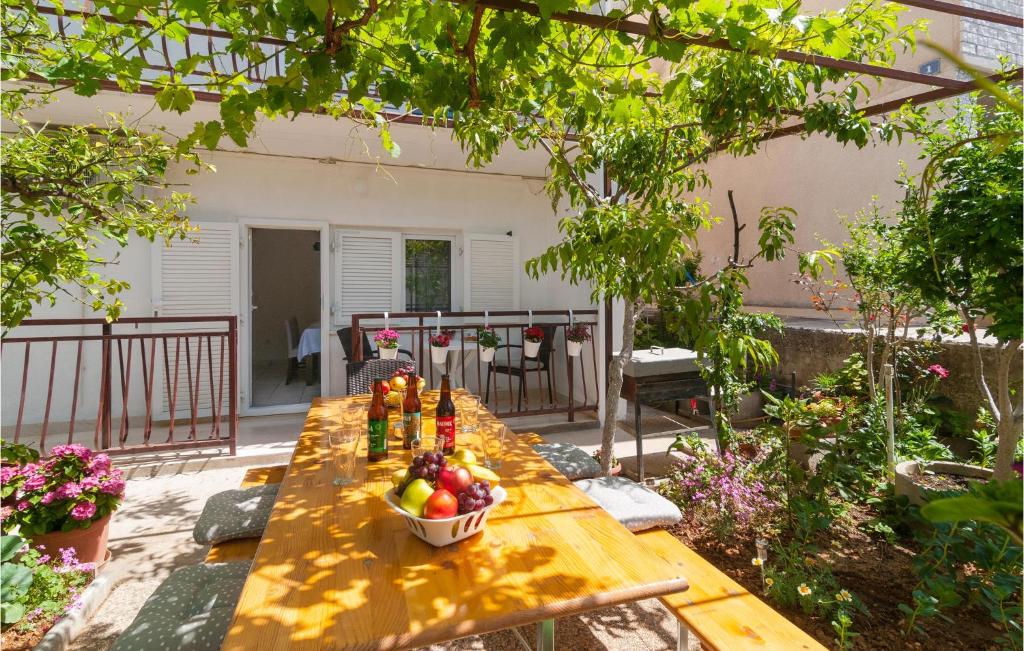 einen Holztisch mit einer Obstschale auf einer Terrasse in der Unterkunft Amazing Apartment In Dugi Rat With Kitchen in Dugi Rat