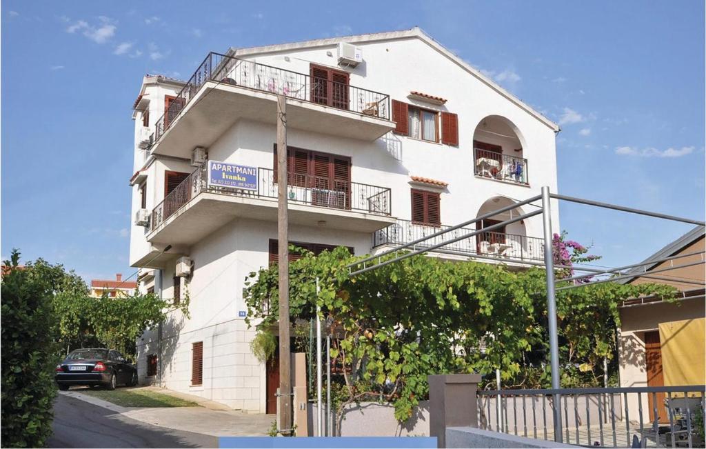 un edificio blanco con balcones y un coche en una calle en Pet Friendly Apartment In Zadar With Kitchen en Zadar