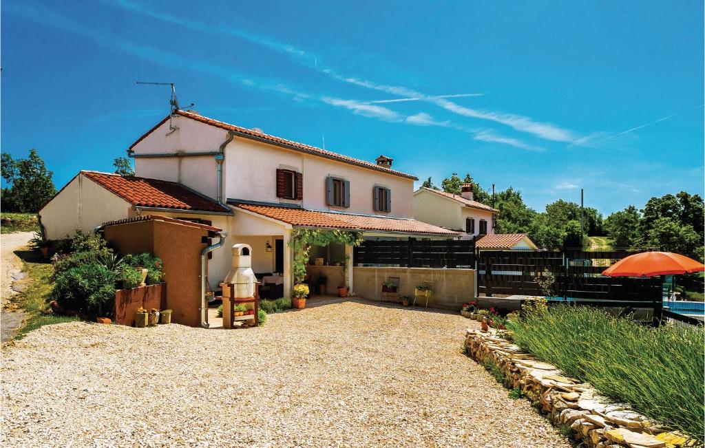 Biały dom z pomarańczowym parasolem przed nim w obiekcie One-Bedroom Holiday Home In Bartici w mieście Barbići