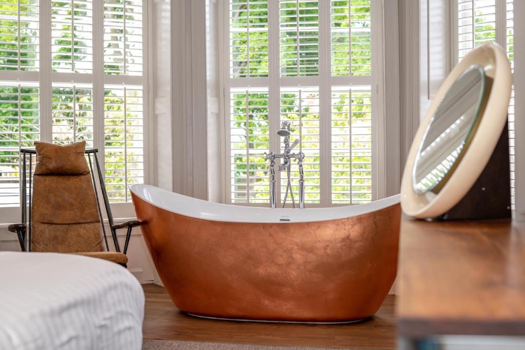 a large tub sitting in a room with a mirror at The Lodge in Hunstanton