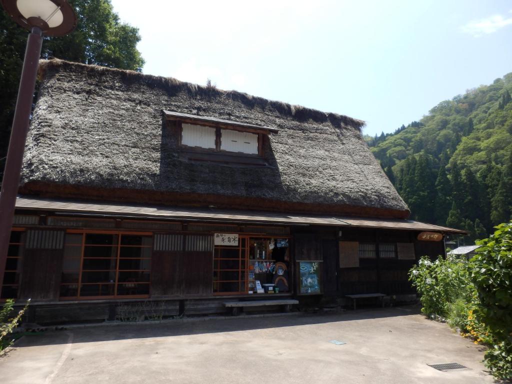 un edificio con techo de paja y luz de la calle en Minshuku Yomoshirou en Nanto