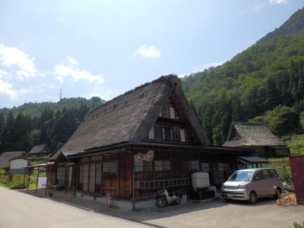 ein Gebäude mit einem Strohdach und einem Auto vor dem Haus in der Unterkunft Minshuku Goyomon in Nanto