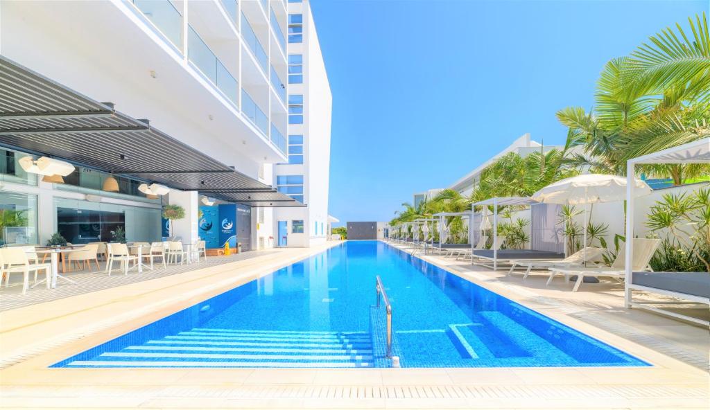 a swimming pool in a building with chairs and umbrellas at Seasons Hotel (Adults Only) in Ayia Napa