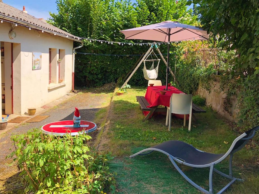 uma mesa e cadeiras e um guarda-sol num quintal em Maison de 6 chambres avec jardin et wifi a La Caillere Saint Hilaire em Mérigny