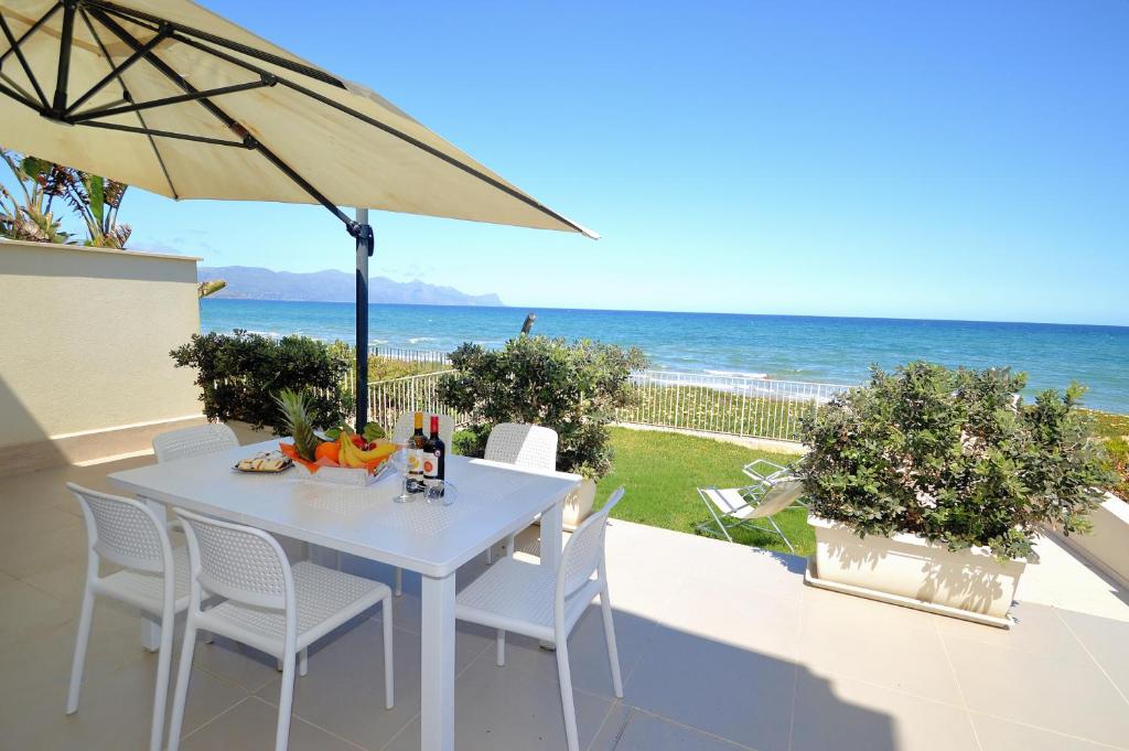 a white table and chairs on a balcony with the ocean at La Dimora di Venere in Alcamo