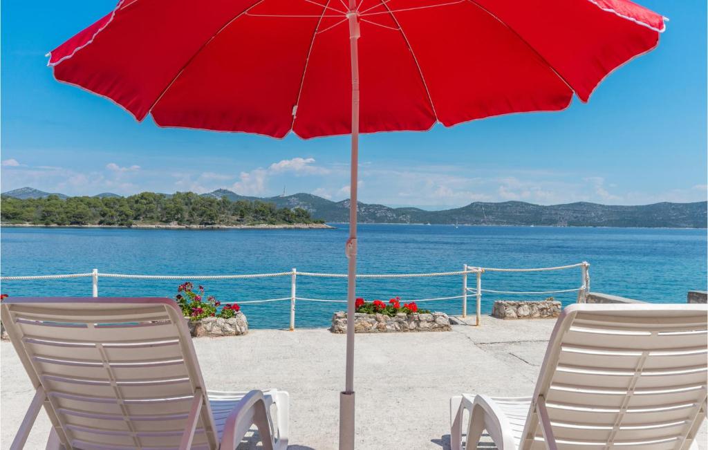 two chairs and a red umbrella on a beach at Amazing Home In Mali Iz With 2 Bedrooms in Iž Mali