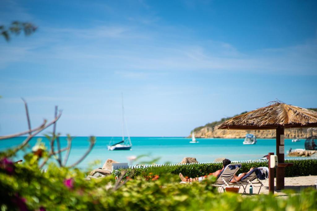Antigua Village Beach Resort في سانت جونز: شاطئ فيه كراسي ومظلة ومحيط