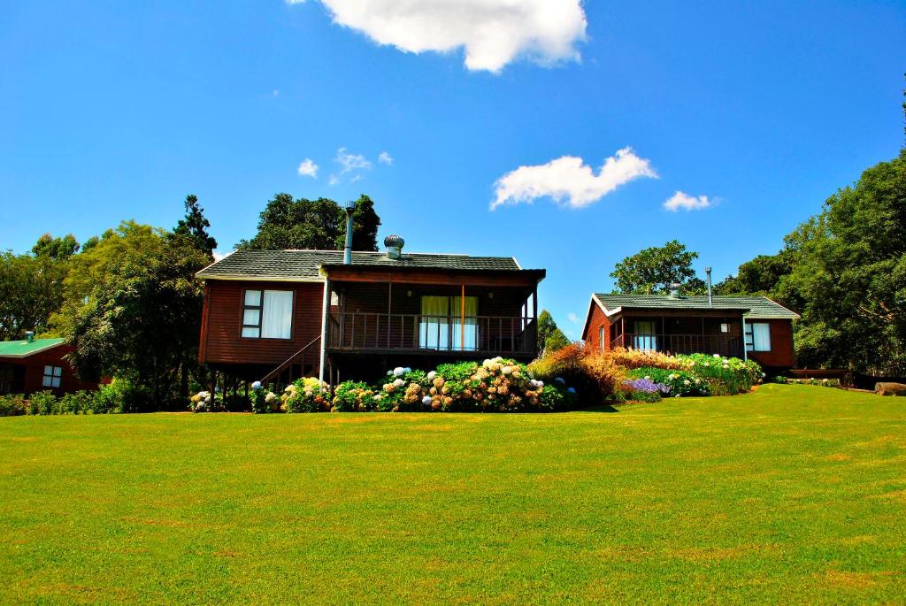 a house on a green field with a yard at Forest View Cabins in Tzaneen