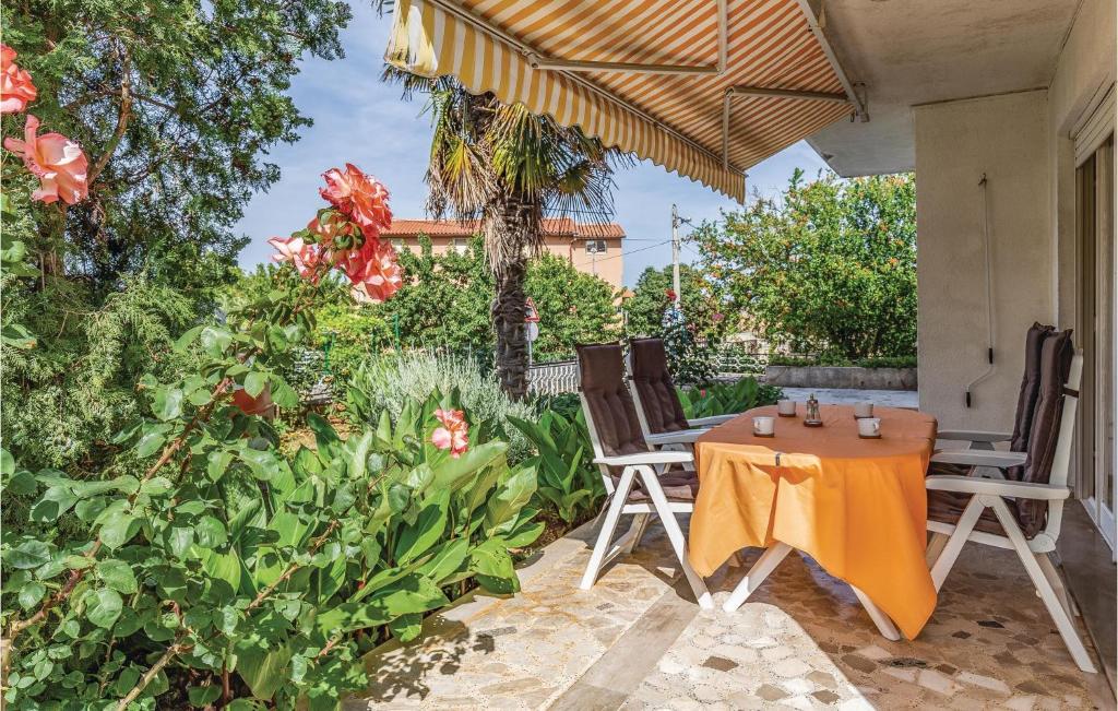 a patio with two chairs and an orange table and umbrella at Cozy Apartment In Medulin With Wifi in Medulin