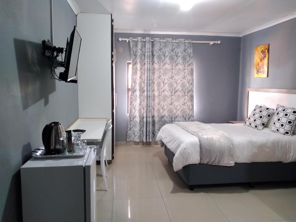 sypialnia z łóżkiem, biurkiem i oknem w obiekcie Legugu Bed and Breakfast w mieście Nongoma