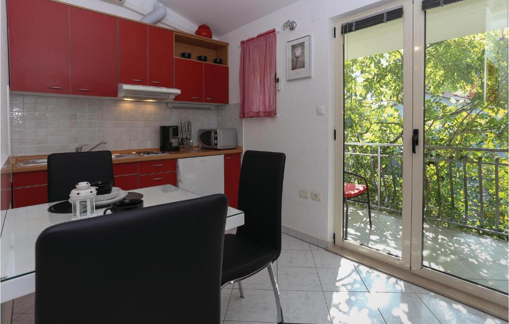 a kitchen with red cabinets and a table with chairs at Nice Apartment In Arbanija With 1 Bedrooms And Wifi in Trogir