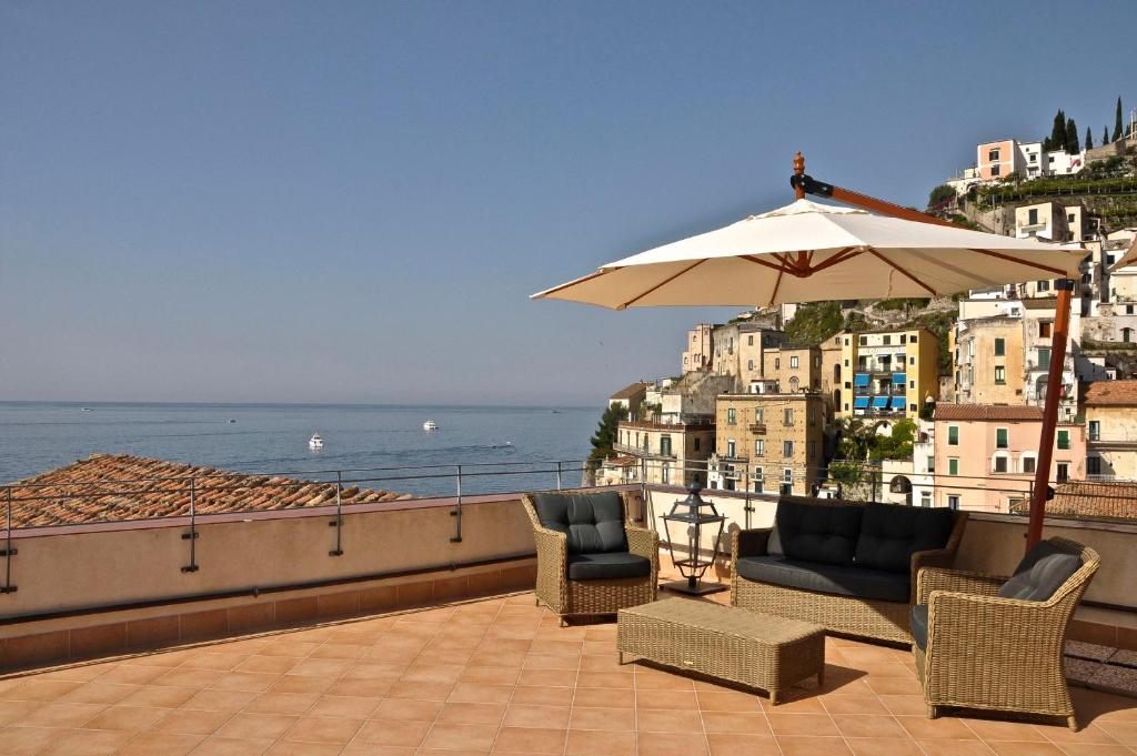 een patio met stoelen en een parasol en de oceaan bij La Zinefra Amalfi Dreams in Minori