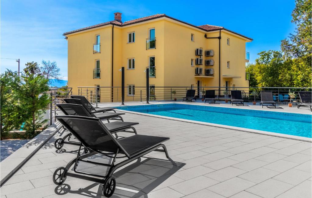 un grupo de sillas sentadas en un patio junto a una piscina en 3 Bedroom Amazing Apartment In Kostrena, en Žurkovo