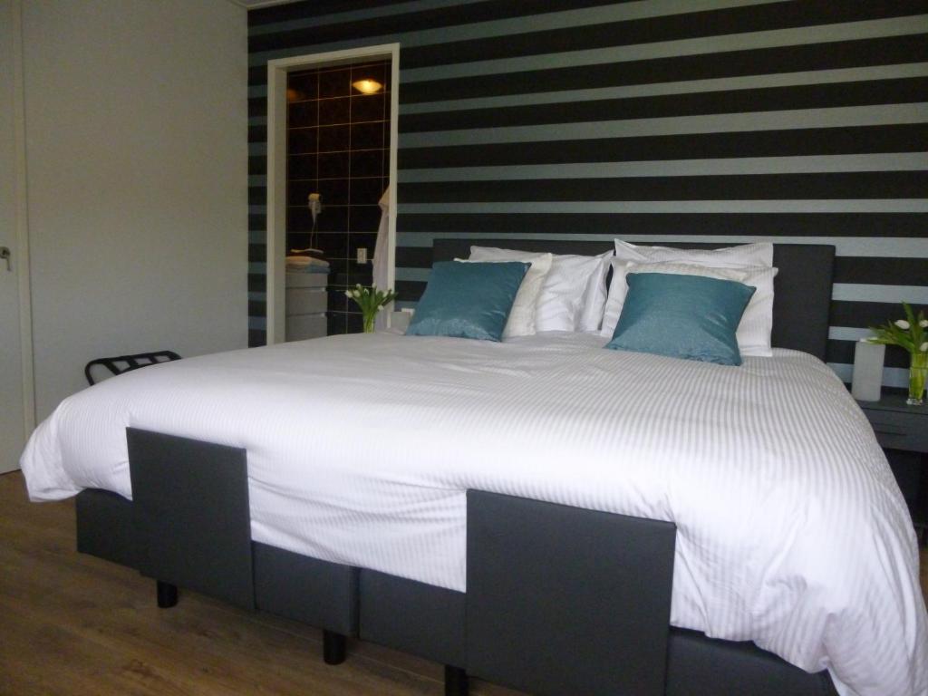 een groot bed met witte lakens en blauwe kussens bij De Langenlee in Zwolle
