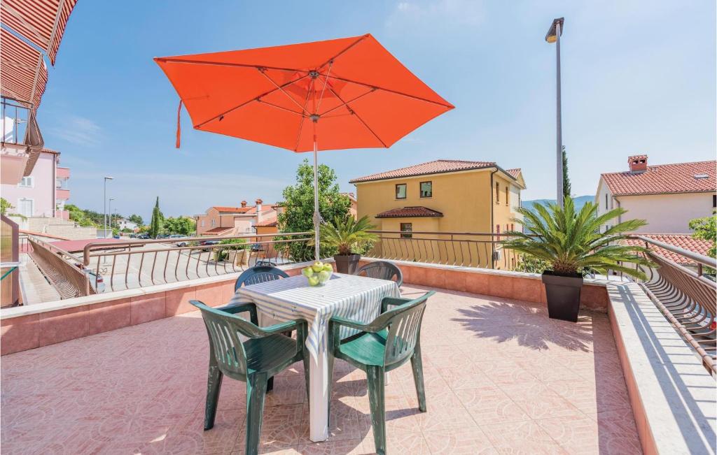 uma mesa e cadeiras com um guarda-sol vermelho na varanda em Gorgeous Apartment In Rabac With Kitchen em Rabac