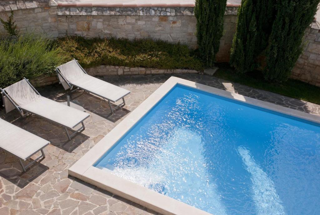a swimming pool with two chairs and a table at Villa Maslinova Grana in Vabriga