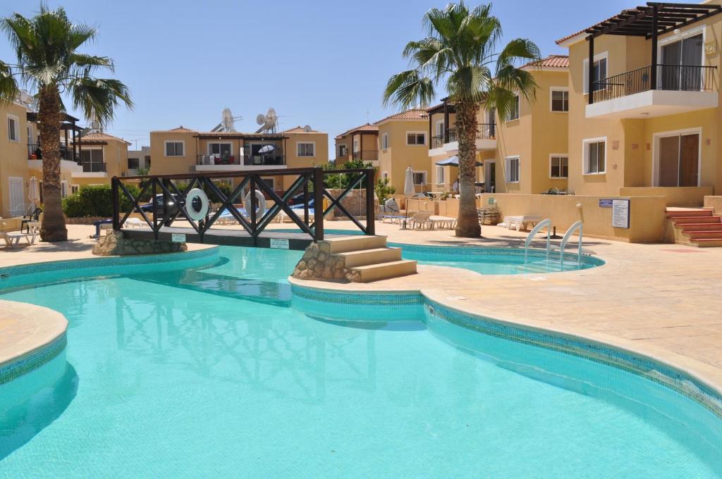 una piscina en un complejo con palmeras y edificios en Sirena Sunrise, Apartment 4, en Pafos