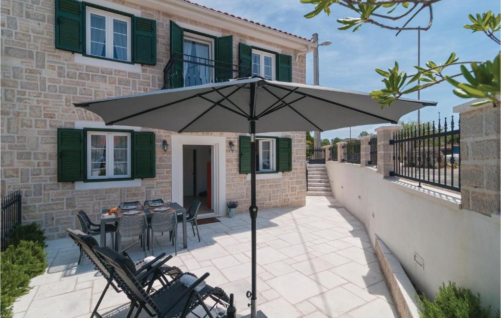 un patio con mesa, sillas y sombrilla en Stunning Home In Primosten With Kitchen, en Primošten