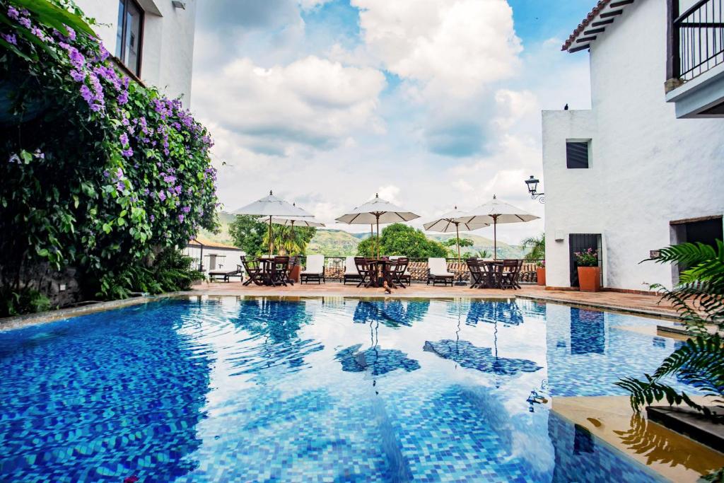 a swimming pool with tables and umbrellas next to a building at Hotel Boutique Posada Las Trampas in Honda