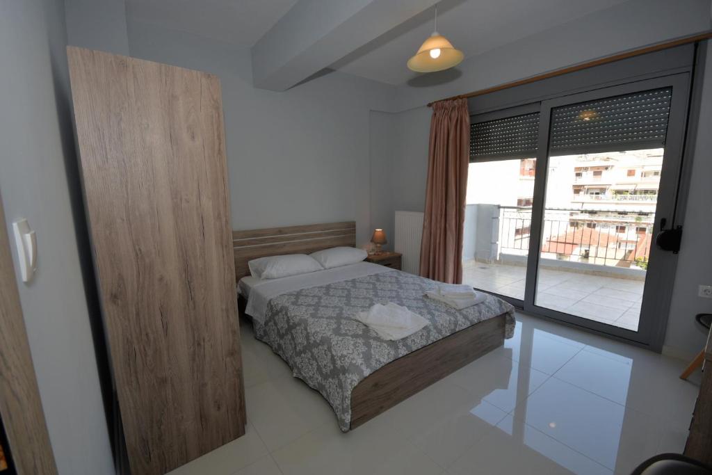 a bedroom with a bed and a large window at APOSTOLIAS APARTMENTS in Volos