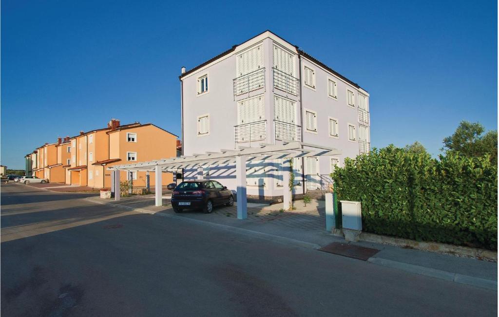 - un grand bâtiment blanc avec une voiture garée à côté dans l'établissement Apartment Vodnjan Peroj Iii, à Vodnjan