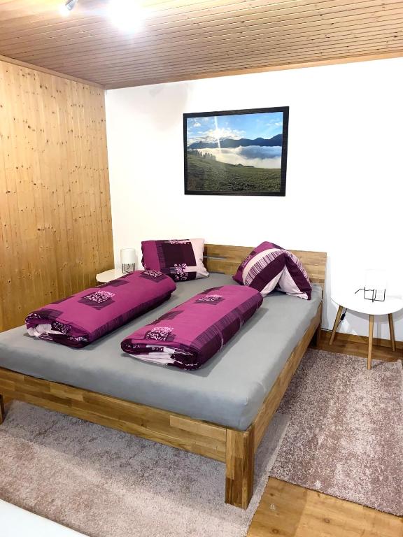 Bett in einem Zimmer mit lila Kissen darauf in der Unterkunft Günstig und Einfaches Studio auf dem Bauernhof in Zuoz
