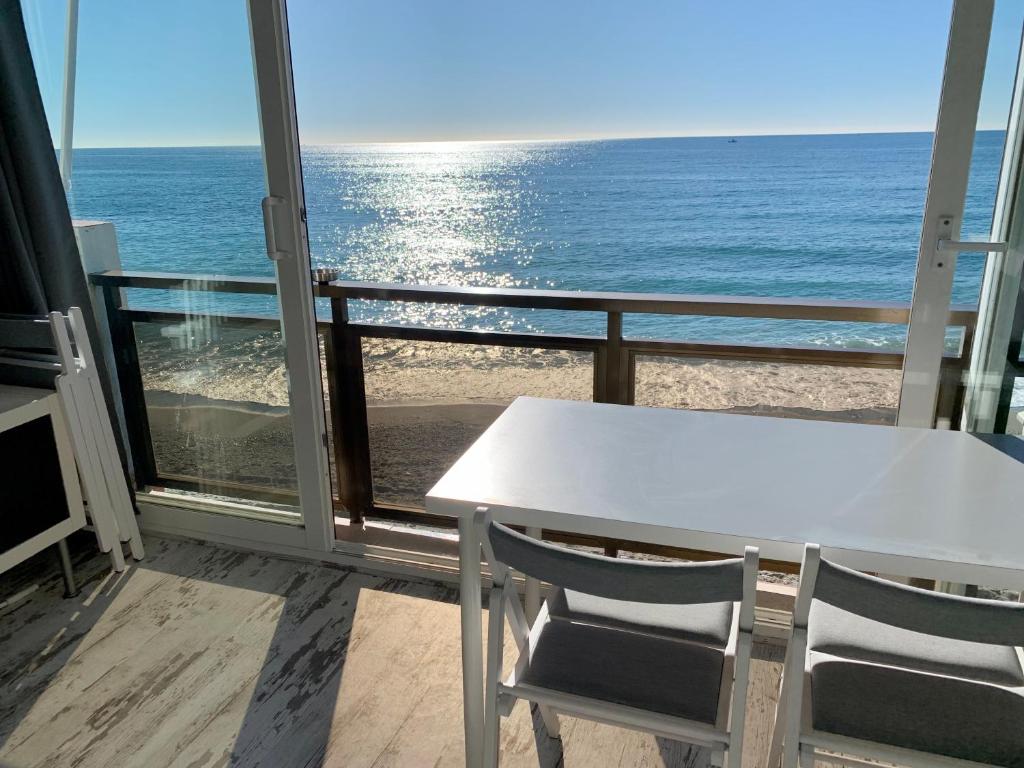 una mesa blanca y sillas en un balcón con vistas al océano en Malibu - “Vive en la playa” “Live on the beach”, en Benalmádena