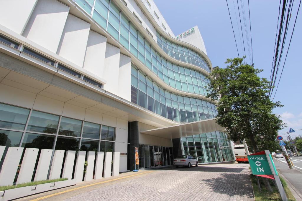 un edificio de oficinas con un coche aparcado fuera de él en Hotel Mielparque Kumamoto en Kumamoto