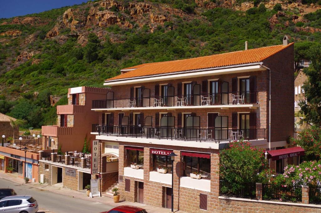 a building on a street with a mountain in the background at Hôtel Idéal in Porto Ota