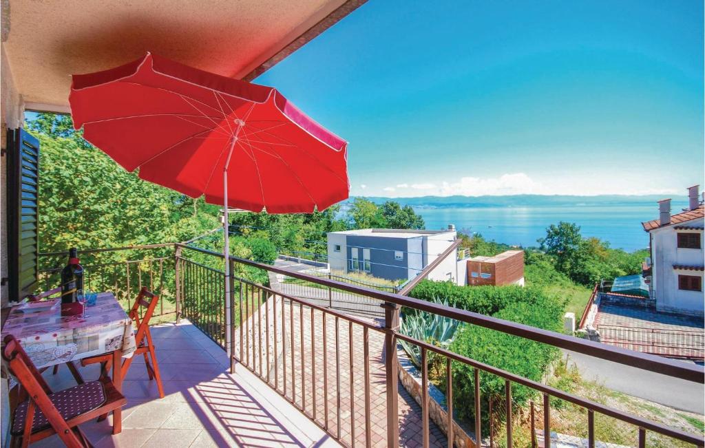 balkon z czerwonym parasolem i stołem w obiekcie Awesome Apartment In Lovran With House Sea View w mieście Lovran