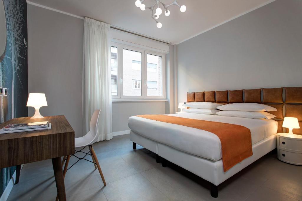 a white bedroom with a bed and a desk and a bed sidx sidx sidx sidx at Noba Hotel e Residenze in Rome