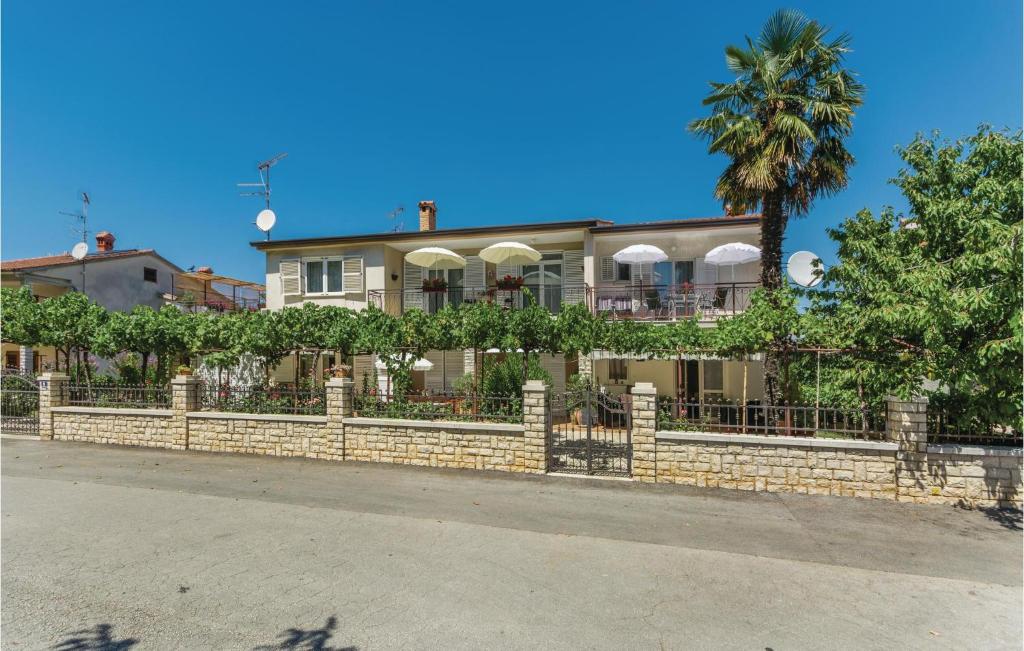 a house with a stone fence and a palm tree at 2 Bedroom Nice Apartment In Porec in Poreč