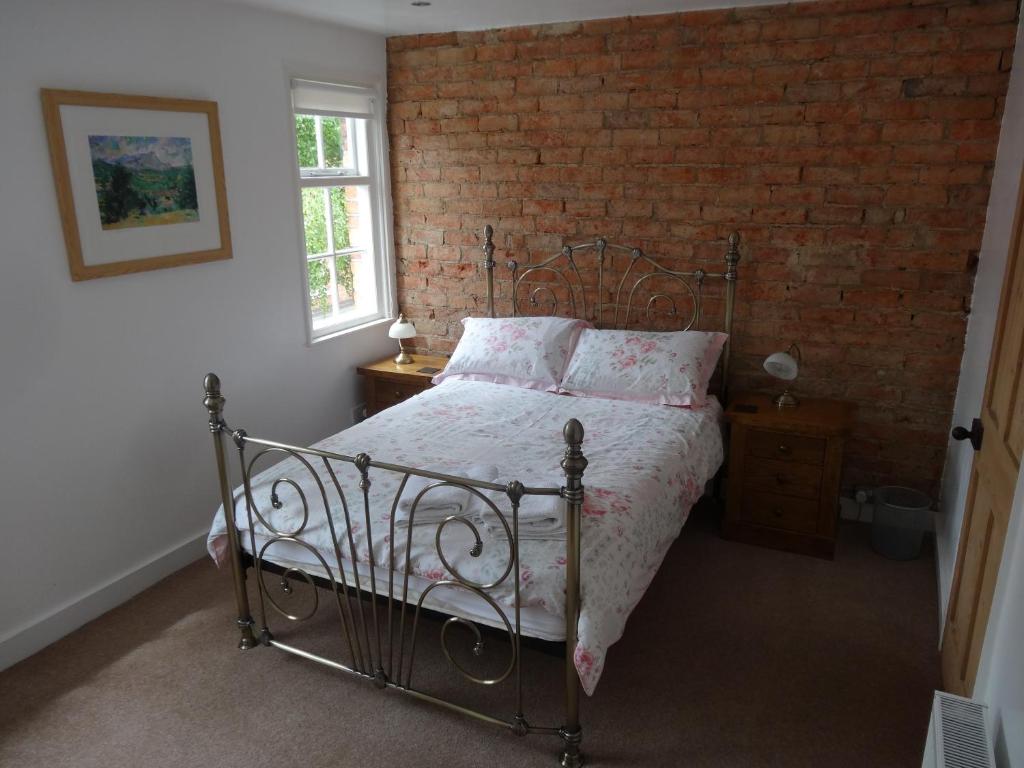 林肯的住宿－磨房路22度假屋酒店，一间卧室设有一张床和砖墙