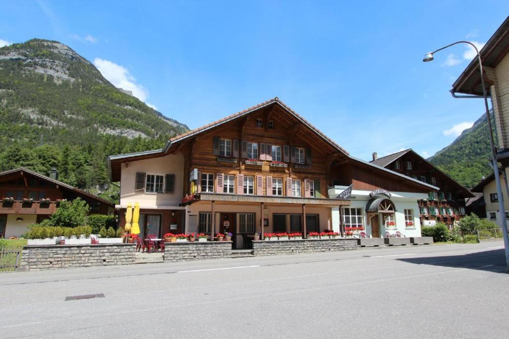 a large wooden building with mountains in the background at Hotel-Restaurant Alpina in Innertkirchen