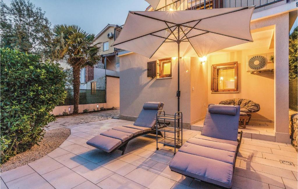 patio z 2 krzesłami i parasolem w obiekcie Holiday Home Medulin Ii w Medulinie