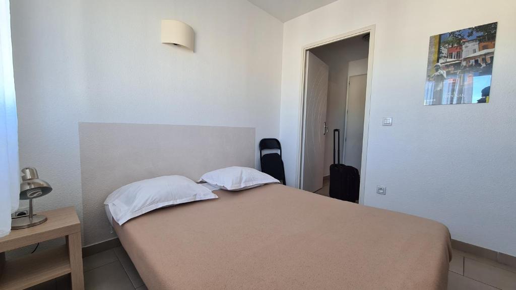 a small bedroom with a bed and a table at Logesty Studio Cosy316 in Perpignan