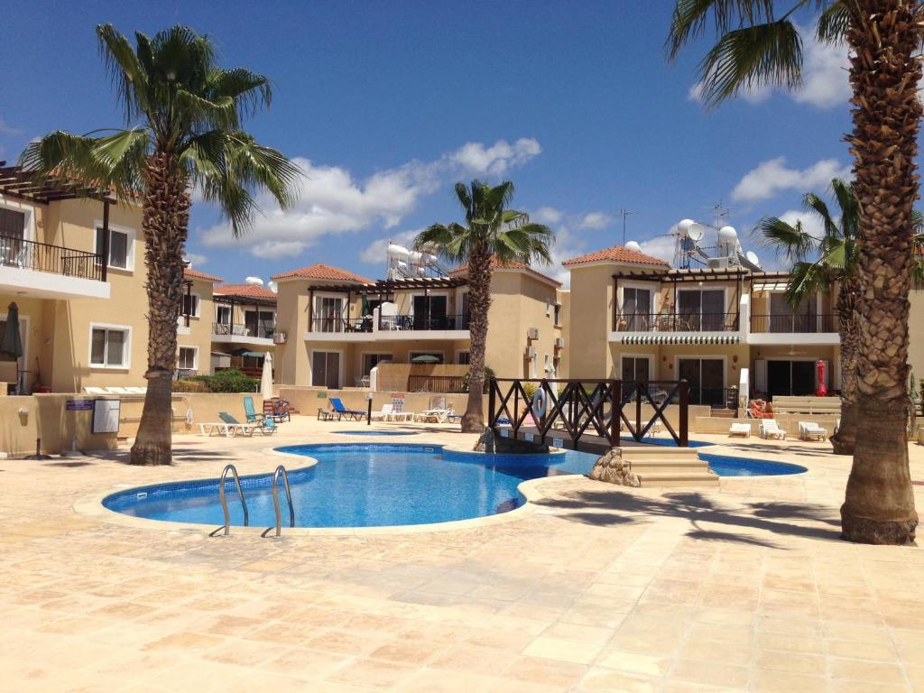 a swimming pool with palm trees and buildings at Sirena Sunrise 120 in Paphos