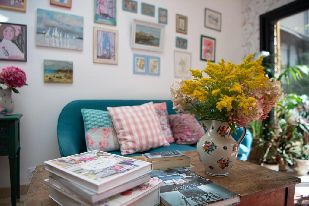 a table with books and a vase with flowers on it at Maison Léontine in Bernay