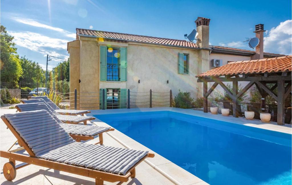 a villa with a swimming pool and lounge chairs at Pet Friendly Home In Malinska With Outdoor Swimming Pool in Malinska
