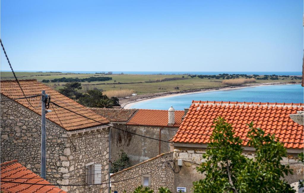 eine Gruppe von Gebäuden mit roten Dächern und einem Strand in der Unterkunft Stunning Home In Unije With Wifi in Unije