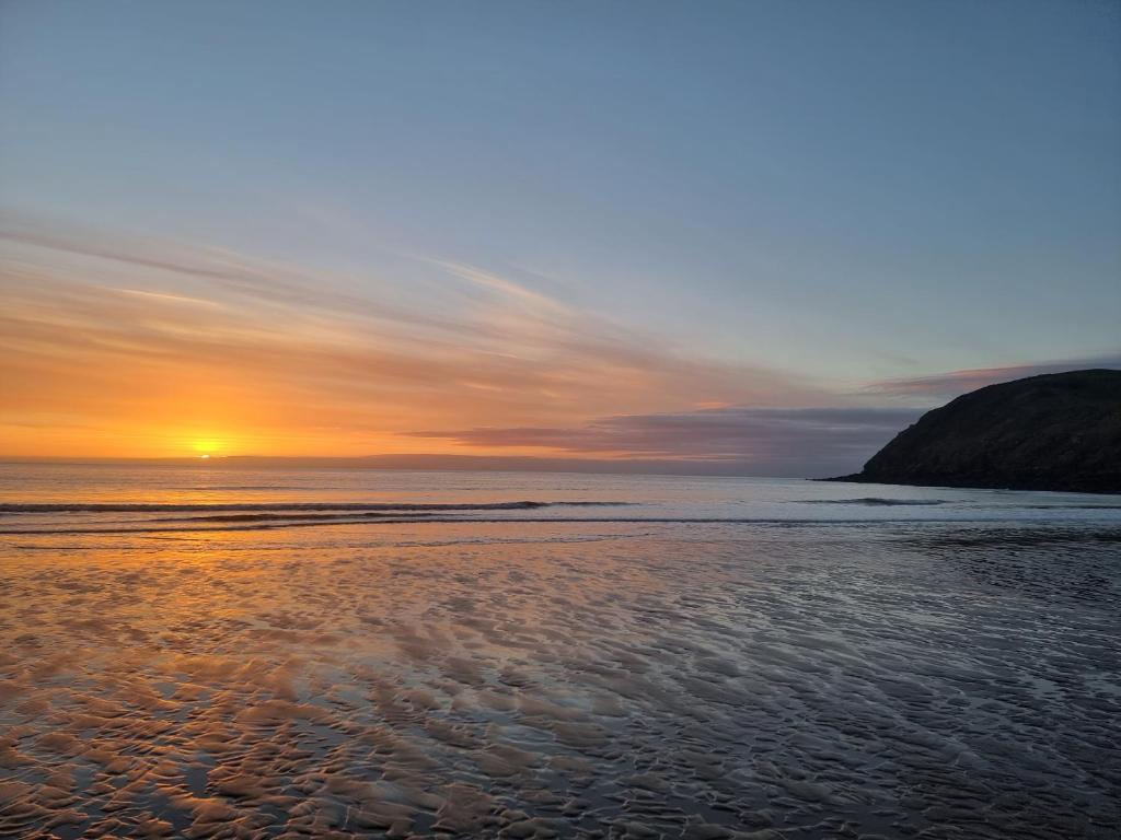 a sunset on a beach with the ocean at Impeccable Beachfront 2-Bed Cottage in St Bees in St Bees