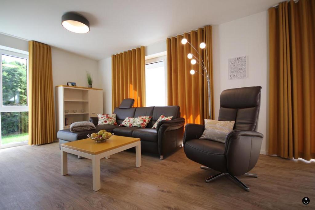 uma sala de estar com um sofá, cadeiras e uma mesa em Refugium 6 em Kellenhusen