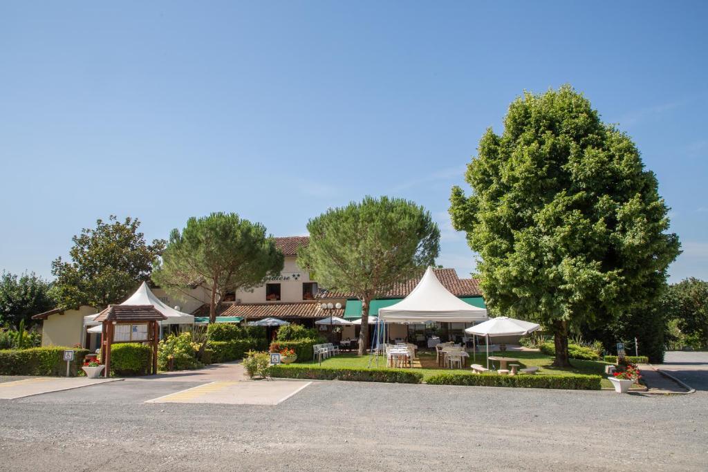 ein Resort mit Tischen und Sonnenschirmen auf einem Parkplatz in der Unterkunft Logis Hôtel et Restaurant La Bombardière in Cuq-Toulza