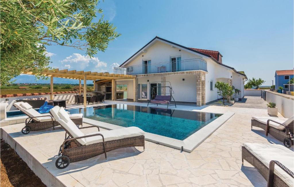 uma piscina com cadeiras e uma casa em Awesome Home In Vrsi With 5 Bedrooms, Wifi And Outdoor Swimming Pool em Vrsi