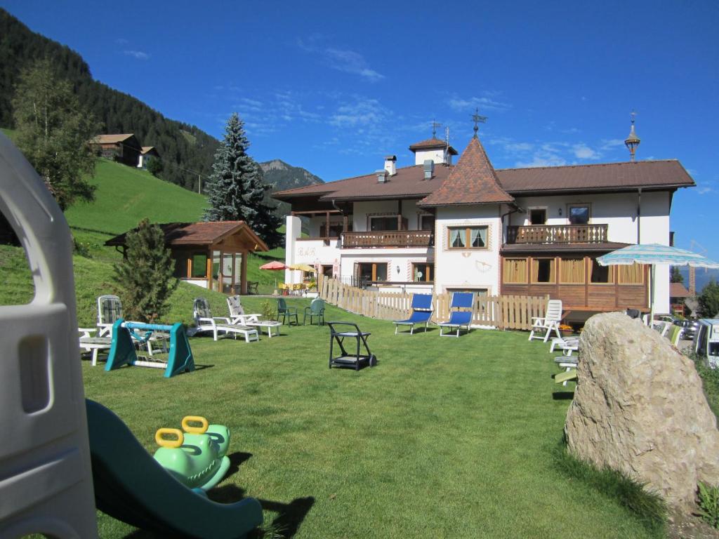 a large yard with chairs and a house at Hotel Ronce in Ortisei