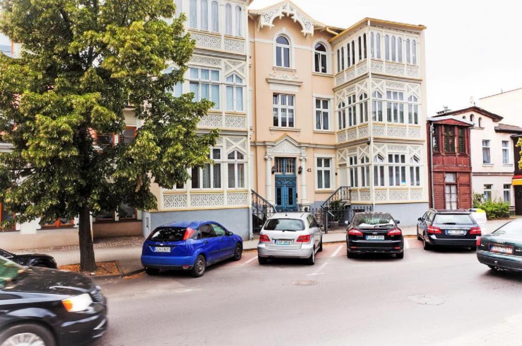ソポトにあるSeashell Apartment (Muszelka) Happy Hoursの建物前に停車する車両群