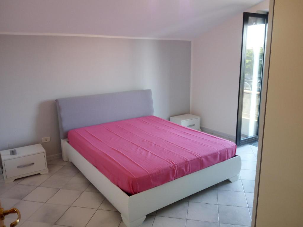um quarto com uma cama com um cobertor rosa em Sant'Andreas house em Santa Maria di Castellabate